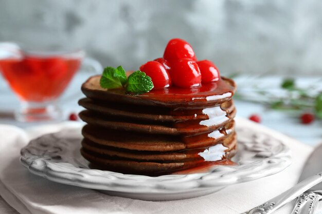 Teller mit leckeren Schokoladenpfannkuchen und Beeren auf dem Tisch