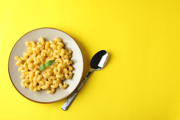 Teller mit Makkaroni und Käse auf gelbem Hintergrund