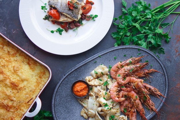 Teller mit Meeresfrüchten, Riesengarnelen und Tintenfisch, Fischmenü im Restaurant, dunkler Hintergrund