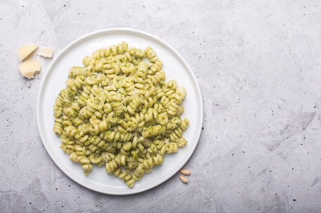 Teller mit Nudel-Fusilli mit Pesto-Sauce auf grauem Betonhintergrund