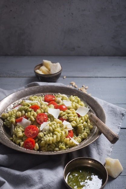 Teller mit Nudel-Fusilli mit Pesto-Sauce auf grauem Holzhintergrund