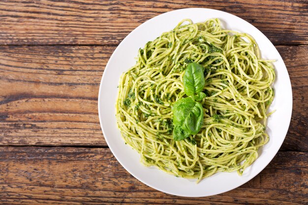 Teller mit Nudeln mit Pesto-Sauce auf Holztisch