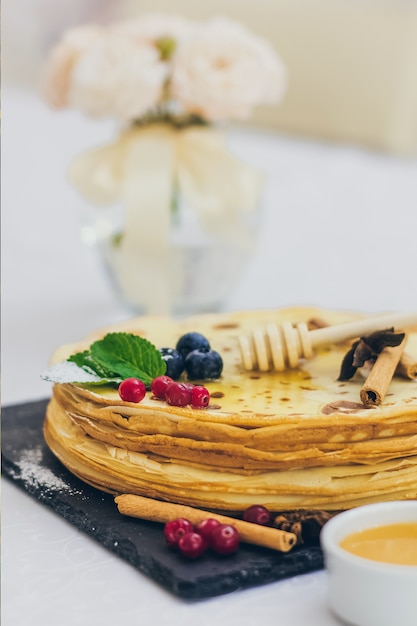 Teller mit Pfannkuchen mit Honig und Preiselbeeren.