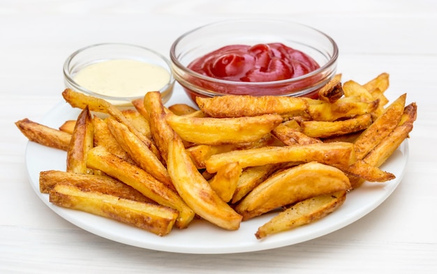 Teller mit Pommes Kartoffelketchup und Mayonnaise auf dem Tisch