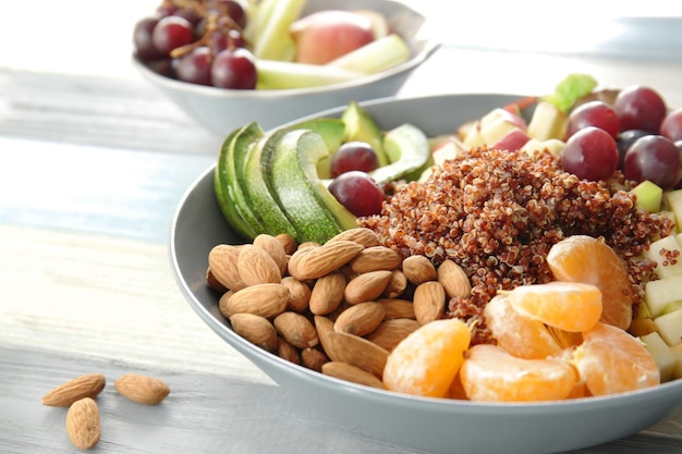 Teller mit Quinoa-Früchten und Mandeln auf Holzhintergrund