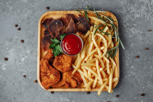 Teller mit Snacks. panierte Chicken Nuggets, Bratkartoffeln und Jamon