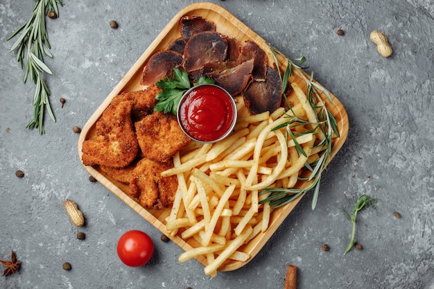 Teller mit Snacks. panierte Hühnernuggets, Bratkartoffeln und Jamon.