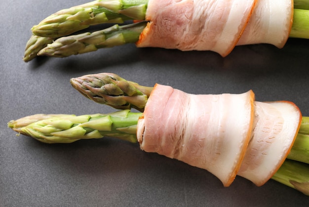 Teller mit Speck umwickelter Spargel auf hellem Hintergrund