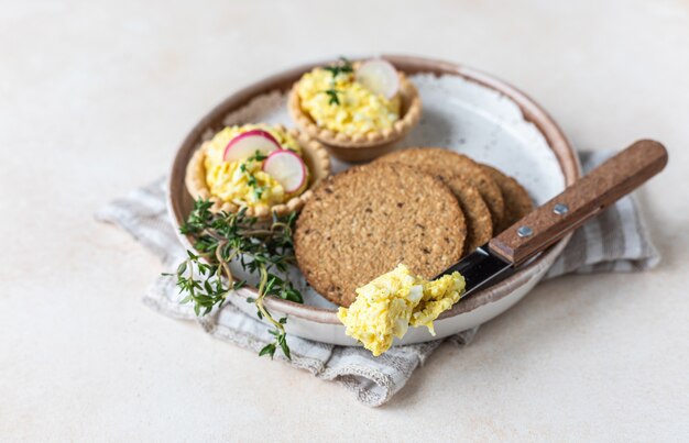 Teller mit Törtchen, Mehrkorncracker mit Eierpastete oder Salat serviert mit Rettich und Thymian.