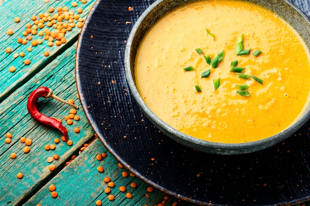 Teller mit vegetarischer roter Linsensuppe auf Holztisch