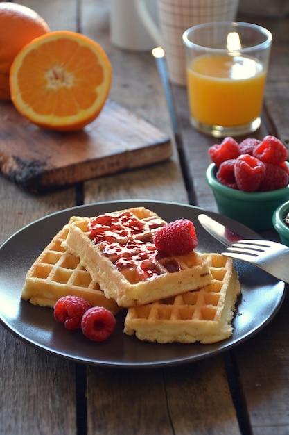 Teller mit Waffeln mit Himbeermarmelade, Orangensaft und Kaffee