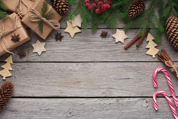 Telón de fondo de Navidad vintage. Paquetes de artesanía, abeto y piruletas sobre fondo de madera rústica, vista superior, espacio de copia