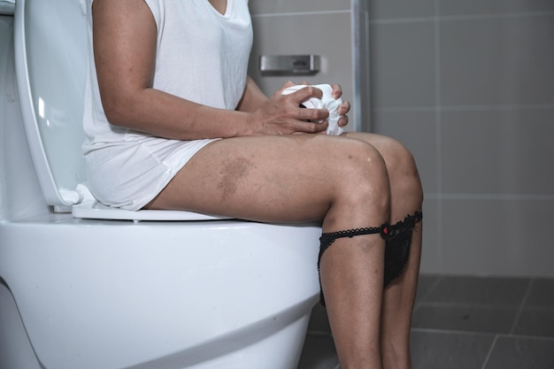 Tem problemas com o conceito de excreçãoUma mulher asiática senta-se no vaso sanitárioConstipação e muito tempo no banheiro