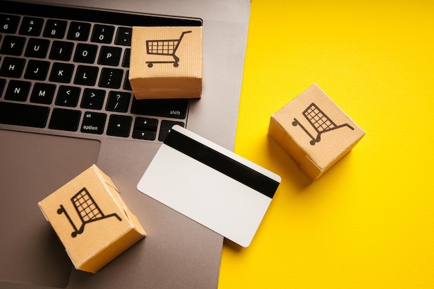 Foto tema de compras y entrega en línea cajas de papel y tarjeta de crédito blanca en un teclado portátil