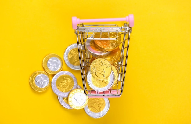 Tema de compras. Mini carro de supermercado con monedas en amarillo.