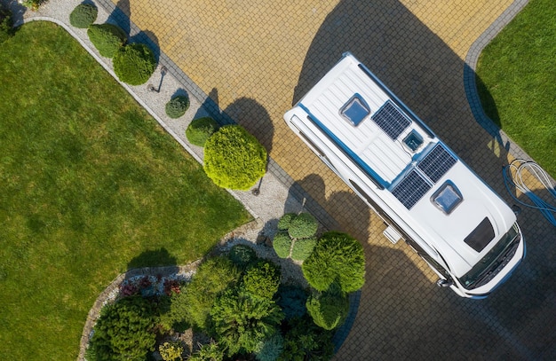 Tema de acampamento e turismo Van de campista moderno com painéis solares instalados Permanecendo na calçada de pedra de paralelepípedos Aguardando a vista aérea do novo destino