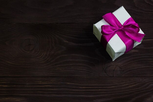 Tema de celebrações e presentes exclusivo presente Embalado em caixa branca com fita roxa presente bonito e caro em fundo escuro de madeira