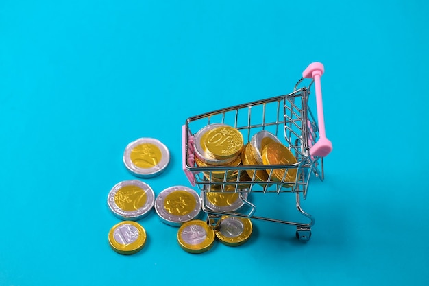 Tema de compras. mini carrinho de supermercado com moedas em bue.