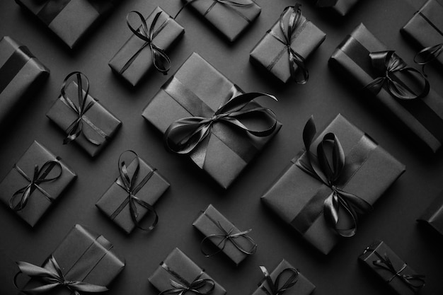 Tema de Natal escuro Presentes em caixas quadradas embrulhadas em papel preto e fita dispostas em fundo preto Vista superior plana