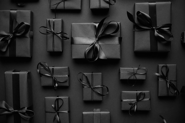 Tema de Natal escuro Presentes em caixas quadradas embrulhadas em papel preto e fita dispostas em fundo preto Vista superior plana