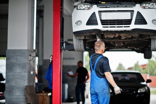 Tema de reparação e manutenção de automóveis Mecânico de uniforme trabalhando em auto serviço