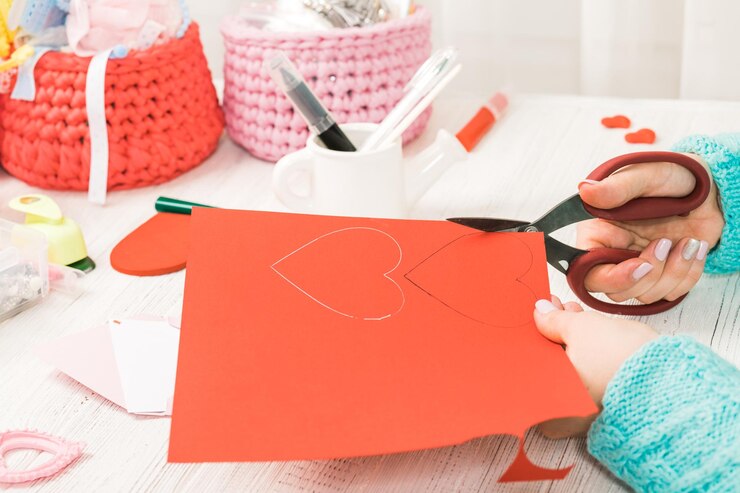 Foto tema del día de san valentín manos femeninas cortan el corazón del papel