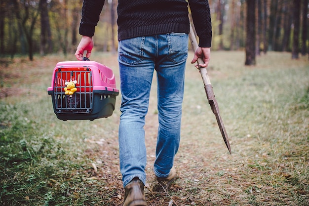 Foto tema del entierro ilegal de mascotas en el bosque. entierro de mascotas en autoservicio en el bosque. el hombre lleva portador con gato o perro muerto y una pala grande para enterrar en el suelo en el bosque. rip animal doméstico.