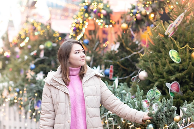 Tema navideño Joven hermosa chica europea sobre un fondo de luces de árbol de Navidad y juguetes en un estado de ánimo alegre felices sueños de regalos