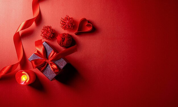 Tema rojo del día de san valentín con caja de regalo envuelta con cinta y corazones de papel