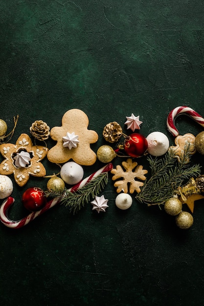 Tema de vacaciones de invierno. Feliz año nuevo. Espacio para texto. Conos de pino de Navidad, ramas de abeto, bastón de caramelo, pan de jengibre sobre fondo verde. Concepto de navidad. Concepto festivo plano