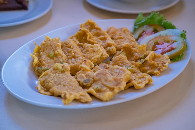 Foto tempeh frito o tempe goreng alimento tradicional indonesio hecho de soja fermentada en un plato blanco