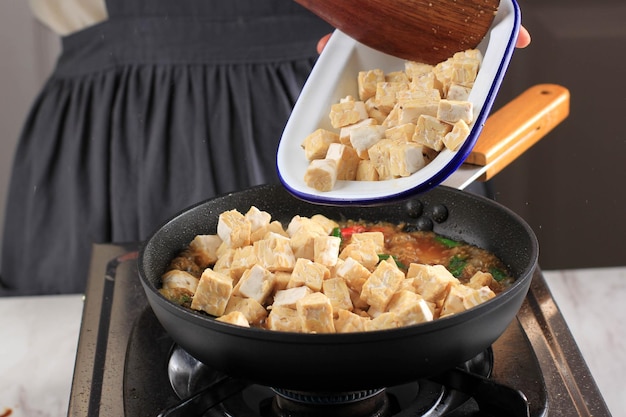 Tempeh Tempe in die Pfanne geben Traditionelles indonesisches Essen aus fermentierten Sojabohnen