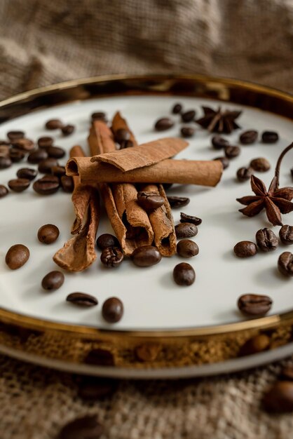 Tempera canela e anis num prato dourado, com grãos de café, fundo de serapilheira.