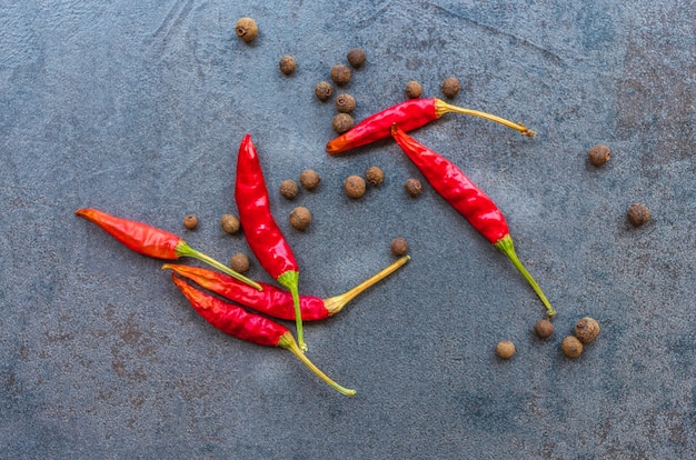 Temperos de pimenta preta e pimenta vermelha em uma tábua de corte feita de pedra escura