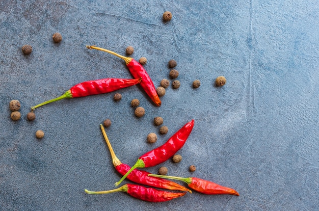 Temperos de pimenta preta e pimenta vermelha em uma tábua de corte feita de pedra escura