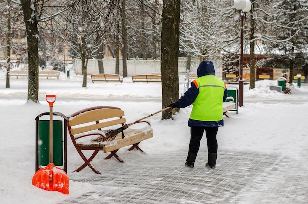 Tempestade de neve na cidade Estradas e calçadas cobertas de neve Pá de trabalhador limpa a neve Mau tempo de inverno Limpeza de ruas após a tempestade de neve