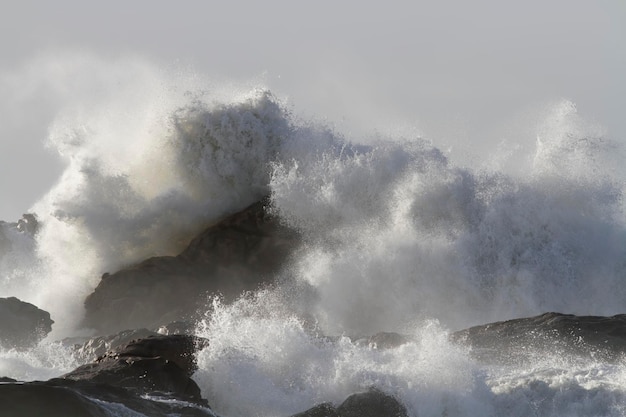 Tempestade na costa vendo grande onda quebrando sobre rochas e penhascos vendo respingos e borrifos