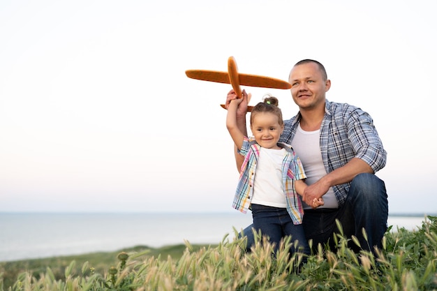 Tempo com a família pai e filha em uma caminhada jogando avião de brinquedo em um fim de semana ao pôr do sol dia de verão natureza homem e menina em pé em uma colina ou montanha acima do mar Conceito de paternidade