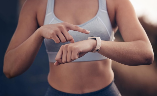 Tempo de condicionamento físico e mulher corredora com um smartwatch rastreando a frequência cardíaca do desempenho da corrida e monitorando dados de treinamento Esportes apontando e atleta feminina verificando o progresso do exercício ou treino cardiovascular