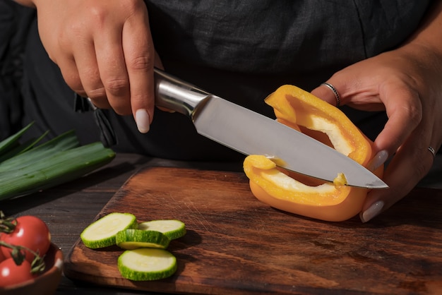 Foto tempo de cozimento. foto de close-up de mãos segurando pimenta orgânica. jovem wooman na cozinha preparando comida.