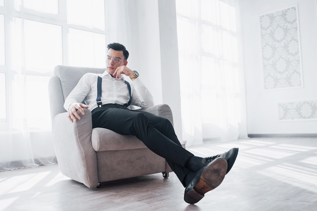 Tempo de descanso. foto de cara atraente de óculos e desgaste elegante, sentado na cadeira.