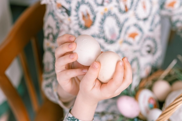 Tempo de férias da páscoa na primavera, as mãos tradicionais das crianças estão algemando, chocalhando ou despejando ovos, família feliz, crianças sinceras, irmãs, meninas, divirtam-se em casa, tradição religiosa