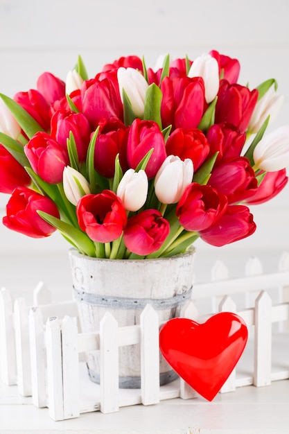 Foto tempo de primavera. buquê de tulipa vermelha na mesa de madeira branca.