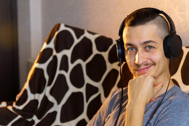 Tempo de relaxar homem barbudo em fones de ouvido ouvindo música homem feliz relaxando no sofá na sala de estar