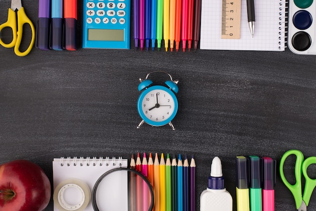 Tempo para o conceito de escola. foto de vista aérea superior acima do relógio no centro e papel de carta colorido acima e abaixo dele isolado no quadro-negro com copyspace