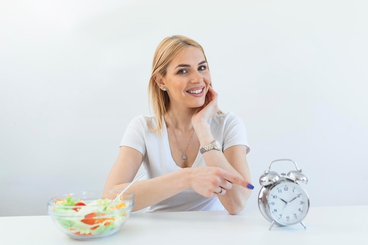 Tempo para perder peso controle de alimentação ou tempo para dieta conceito relógio despertador retro em que a mulher fazer jejum intermitente com uma comida saudável de salada