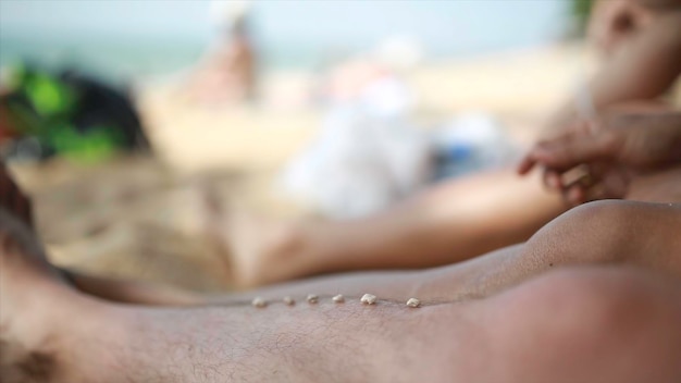 Tempo preguiçoso pés do homem na praia na areia em um dia de verão cada um coloca um grão de areia sobre o