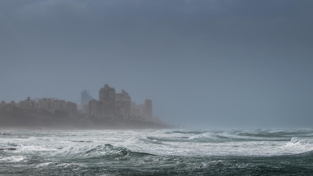 Tempo tempestuoso à beira-mar com grandes ondas e silhuetas de edifícios no banco alto Bat Yam Israel