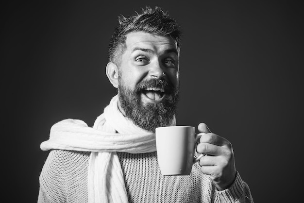 Temporada de bebidas y concepto de personas feliz hombre barbudo sonriente con taza bebiendo té caliente en invierno