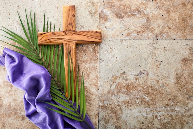 Foto temporada de cuaresma semana santa y concepto de viernes santo hojas de palma y cruz sobre fondo de piedra